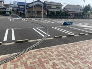 ミニSLの線路を敷いた写真。駐車場の車止めブロックを一つ外して線路を通している。