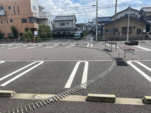 ミニSLの線路を敷いた写真。2024年の写真だが、2025年と同様に、駐車場の車止めブロックを一つ外して線路を通している。